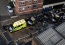 An aerial photograph showing three blackened and burned out ambulances and one badly damaged one, parked outside a building.