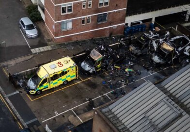 An aerial photograph showing three blackened and burned out ambulances and one badly damaged one, parked outside a building.