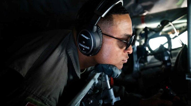 A man in uniform inside a plane, wearing sunglasses and headphones.
