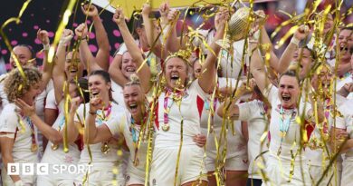 Zoe Aldcroft of England lifts the Women's Rugby World Cup trophy after defeating Canada