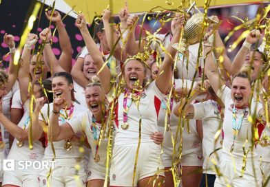 Zoe Aldcroft of England lifts the Women's Rugby World Cup trophy after defeating Canada