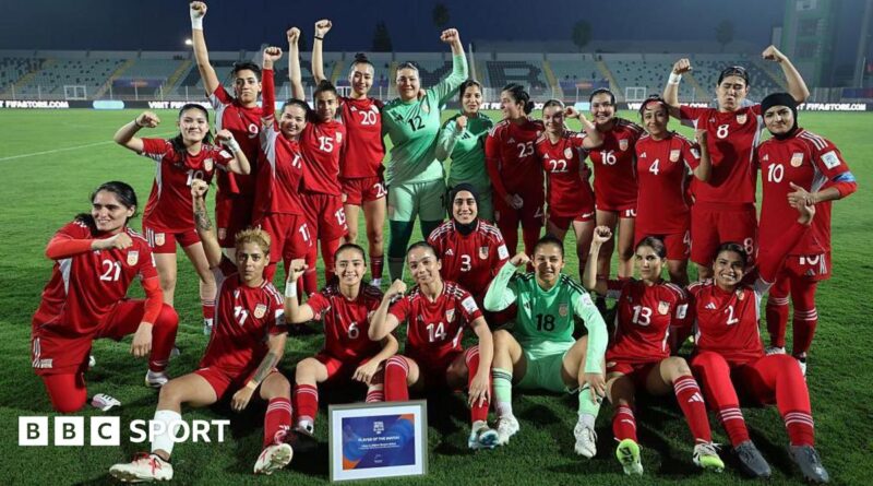 Players from the Afghan Women United team, half standing and half seated, pose for a post-match photo, smiling and with fists raised
