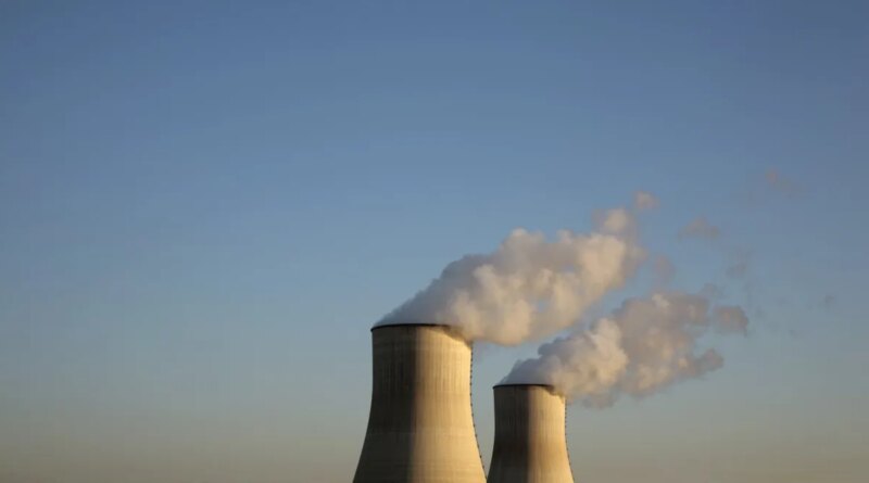 Cooling towers for a nuclear reactor stand against a blue sky.