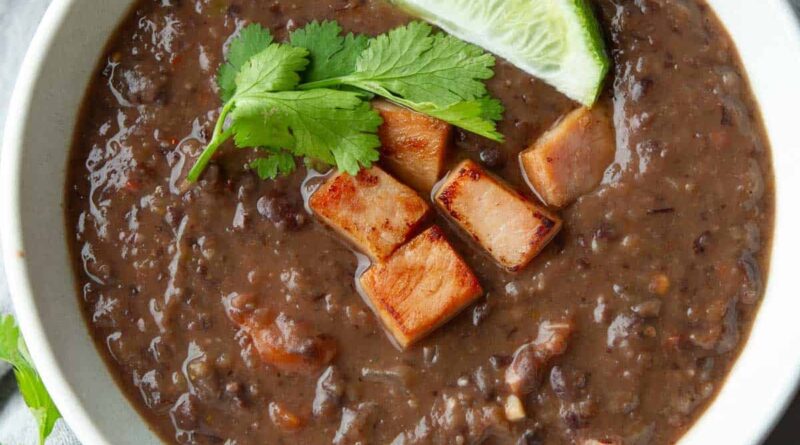 Black bean soup with hame and a lime wedge in a bowl.