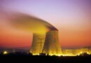 Nuclear power plant cooling towers emit steam at dusk.
