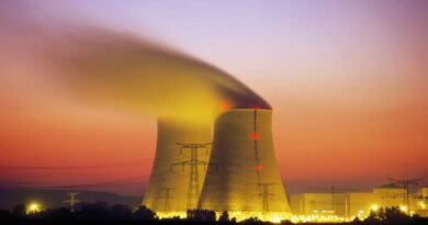 Nuclear power plant cooling towers emit steam at dusk.