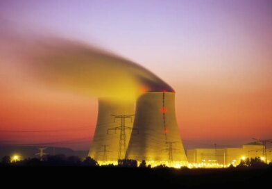 Nuclear power plant cooling towers emit steam at dusk.