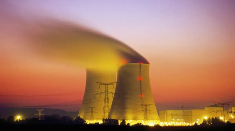 Nuclear power plant cooling towers emit steam at dusk.