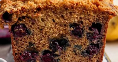 Close-up of a sliced loaf of blueberry banana bread with a crumbly topping, showing visible blueberries inside the moist bread.