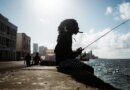 A Havana local smokes a cigar whilst fishing on the Malecón. [Euan Wallace/ Al Jazeera]