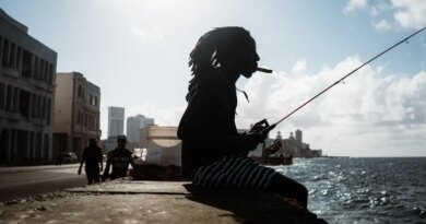 A Havana local smokes a cigar whilst fishing on the Malecón. [Euan Wallace/ Al Jazeera]