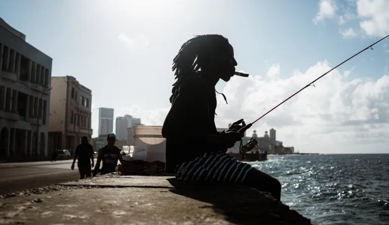 A Havana local smokes a cigar whilst fishing on the Malecón. [Euan Wallace/ Al Jazeera]