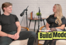 Artisan CEO, Jaspar Carmichael-Jack and Build Mode host Isabelle Johannessen sit facing each other in a podcast studio with microphones, mid-conversation, in front of a white brick wall; a small table with books and a plant sits between them, and a “TechCrunch Build Mode” logo overlay appears in the lower right corner.