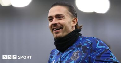 Jack Grealish poses for a photo with five athletes from Special Olympics Great Britain. They are all holding up Everton shirts with '26.2' on. 