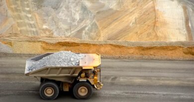 A large yellow dump truck carries ore out of a pit mine.