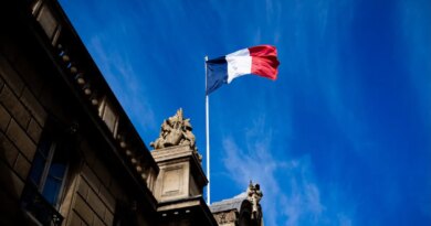 French tricolour flag (blue, white and red, symbol of the Republic of France) hanging from a flagpole above the entrance gate to the courtyard of the Elysee Palace, Exit from the Cabinet meeting at the Presidential Palace of the Elysee in Paris, France on August 27, 2025. The ministers get into their cars and leave the Elysee Palace. (Photo by Amaury Cornu / Hans Lucas via AFP)