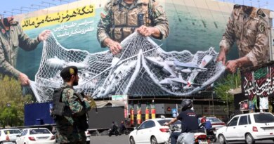 epa12870206 A member of the Iranian security forces watches over traffic passing a huge political billboard reading in Persian ’The Strait of Hormuz will remain closed', in Enghelb square in Tehran, Iran, 05 April 2026. Iran's Revolutionary Guards (IRGC) said a US aircraft that had been searching for the crew member of a missing US fighter jet had been destroyed, Iranian media reported on 05 April 2026. EPA/ABEDIN TAHERKENAREH