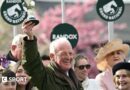 Willie Mullins smiling and holding a trophy in the air