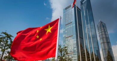 The vibrant red field and yellow stars of the Flag of the People's Republic of China flying in the breeze beside the futuristic glass and steel towers of Pudong's soaring skyscrapers, Shanghai, China.