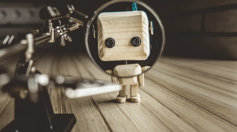 Wooden Robot Android Stands On A Table Under A Magnifying Glass. Metal Clamps With Magnifying Glass