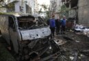 Men look at the damage next to the wreckage of a vehicle at the site of an Israeli strike in Beirut on April 1, 2026.