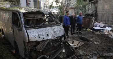 Men look at the damage next to the wreckage of a vehicle at the site of an Israeli strike in Beirut on April 1, 2026.