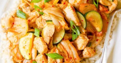 Kimchi chicken stir fry and rice on a white plate.