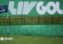 A flag on a golf course green in front of a sign that says 'LIV Golf'