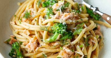 Bucatini noodles with salmon, broccoli and dill in a white bowl.