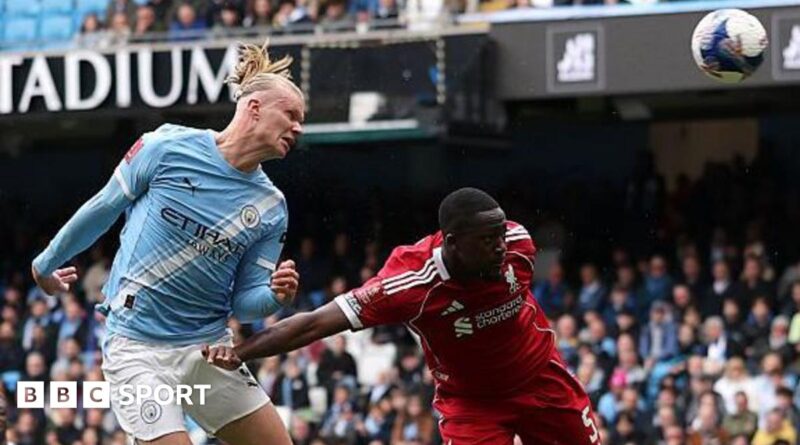 Erling Haaland, wearing Manchester City's light blue kit, celebrates his latest hat-trick by making a three-finger salute with his left hand