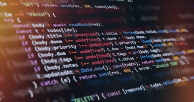 Close-up of computer screen showing colorful programming code lines with syntax highlighting and blurred light reflections.