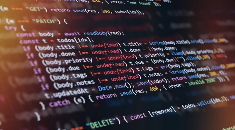 Close-up of computer screen showing colorful programming code lines with syntax highlighting and blurred light reflections.