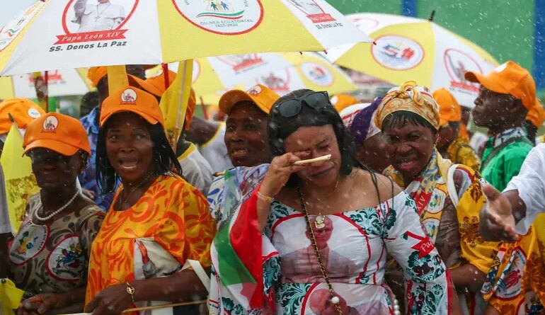 People use umbrellas to shelter from the rain as they wait on a street for Pope Leo XIV to pass by, in Bata, Equatorial Guinea, April 22, 2026. REUTERS/Guglielmo Mangiapane