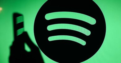 The Spotify logo displays on a screen with a person holding a phone.