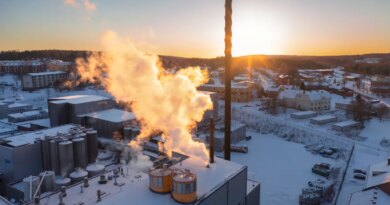 Aerial view of an industrial building in winter with sun lit smoke / steam rising up from the chimneys.