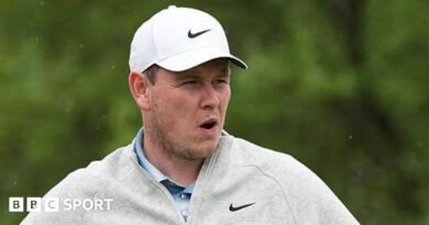 Robert MacIntyre in grey golf fleece and white cap during the final round of the Texas Open, with greenery in the background