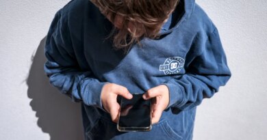 Shows a 14-year-old boy as he looks at social media on his mobile phone.