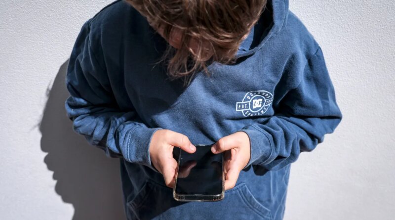 Shows a 14-year-old boy as he looks at social media on his mobile phone.
