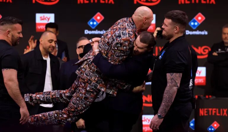 Russia's Arslanbek Makhmudov picks up Britain's two-time former world heavyweight champion Tyson Fury during a press conference in central London on April 9, 2026, ahead of their heavyweight boxing match on April 11. (Photo by Toby Shepheard / AFP)