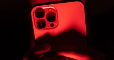 a person holding an iPhone facing the camera in a red backdrop