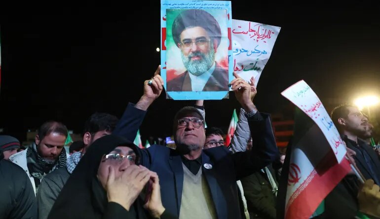 An Iranian man holds up picture of Iranian supreme leader Ayatollah Mojataba Khamenei as others react to a ceasefire announcement at the Enqelab square, in Tehran, on April 8 2026.