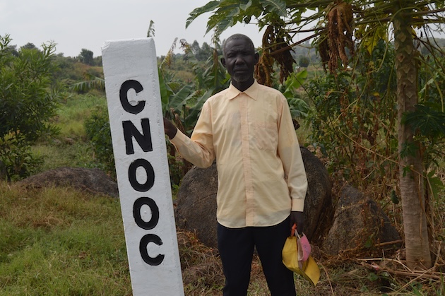 Local farmer Okumu Weke near an EACOP road beacon in Nyamtai village, Kikuube District in the Western Region of Uganda. Credit: Waruru/IPS