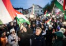 Peter Magyar stands at the head of a large crowd of people, many holding Hungarian flags, in an outdoor setting with buildings in the background.