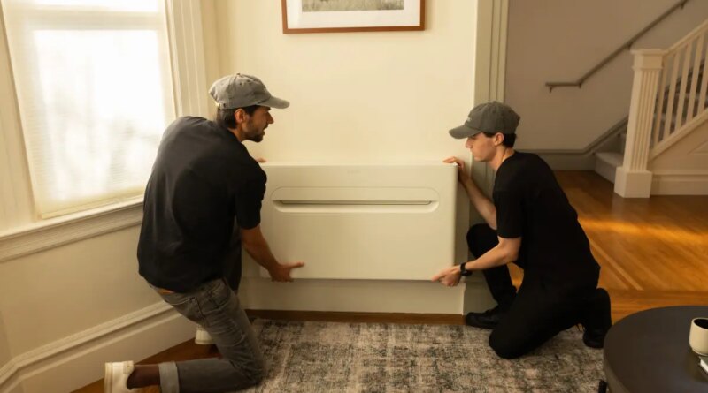 Two men install a heat pump on a wall.