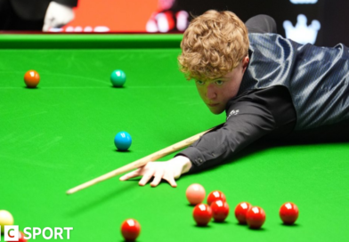 Stan Moody stretches over the snooker table to play a shot