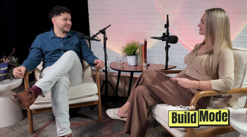 Two people seated in armchairs during a podcast interview, speaking into microphones across a small table with water glasses and a plant, with a “TechCrunch Build Mode” logo overlay in the corner.