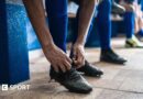 Soccer player tying shoelaces while preparing for match in the locker room