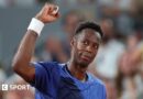 Gael Monfils, wearing a blue t-shirt, looks up to his right and raises his right fist