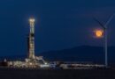 Fervo's drilling rig lit up at night with the moon rising in the background.