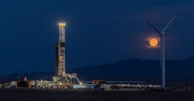 Fervo's drilling rig lit up at night with the moon rising in the background.